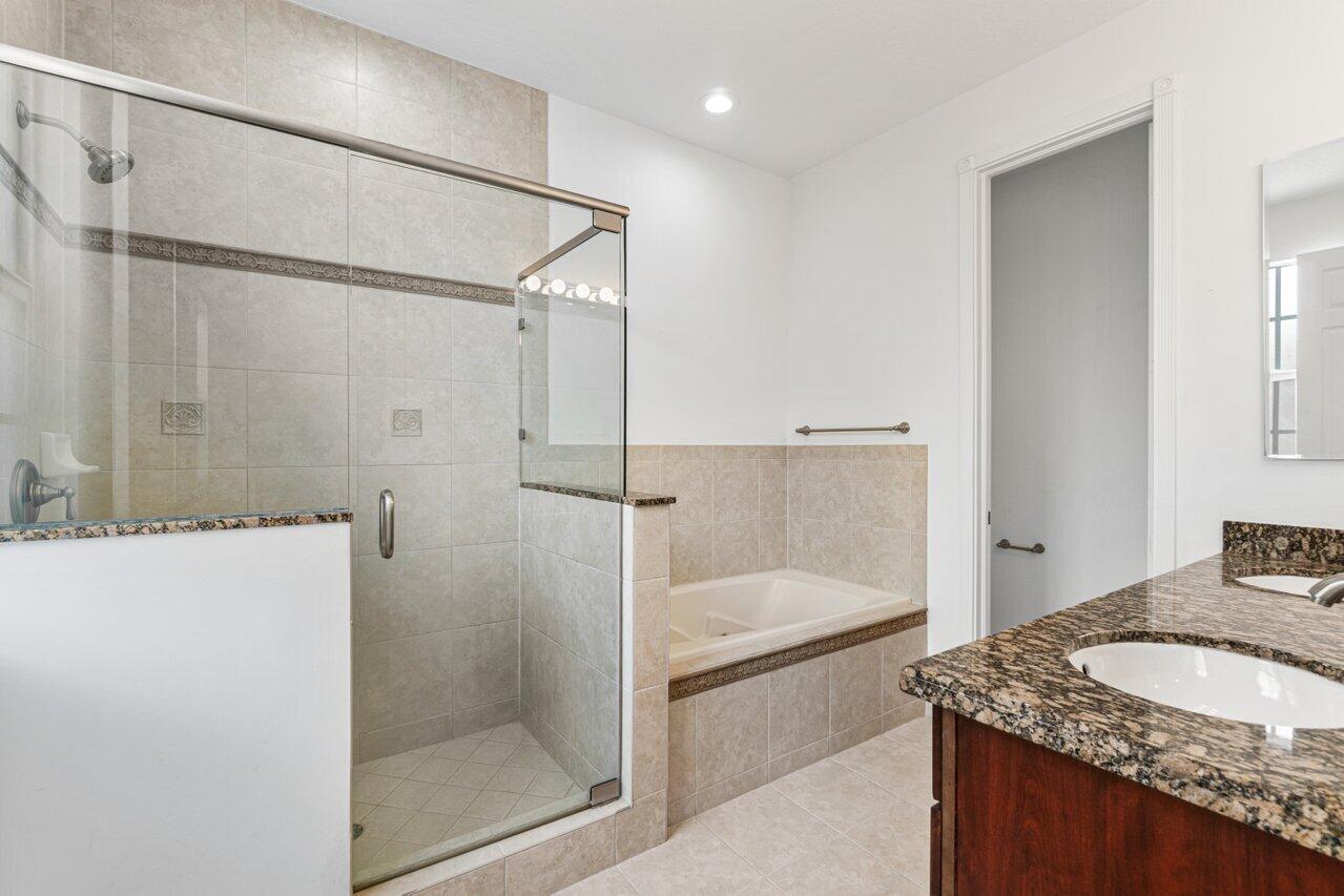 Bathroom with a glass shower, built-in tub, and granite vanity.