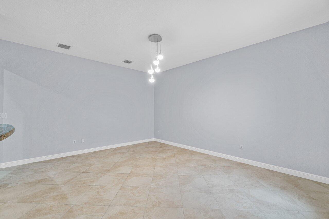 Empty tiled room with pale walls and a modern multi-light pendant fixture.