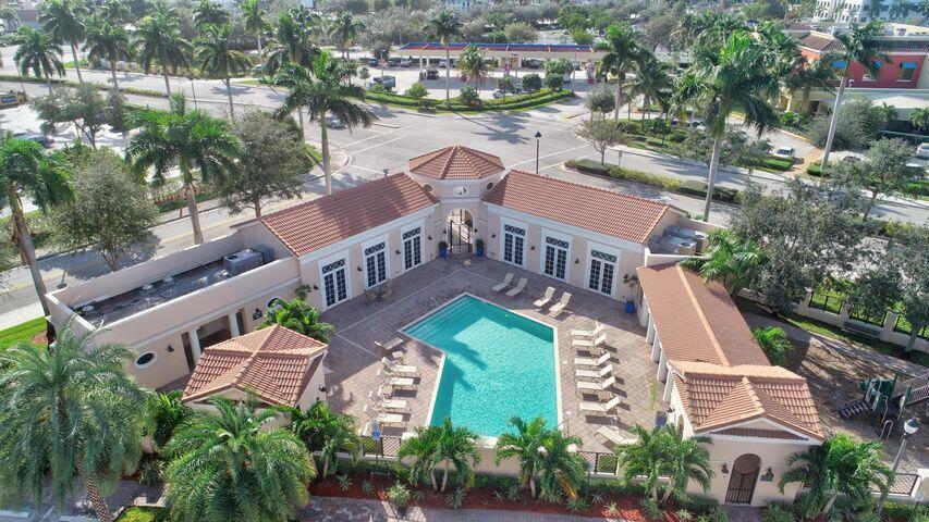 Aerial view of community pool with tiled deck, lounge chairs, and surrounding palm trees.