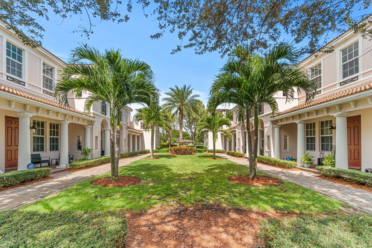 Townhouse courtyard with palm trees, a central lawn, and paved walkways.