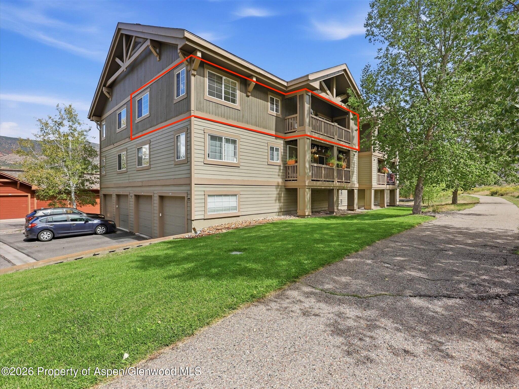 Condominium building with the upper-level unit outlined in red and a private balcony.