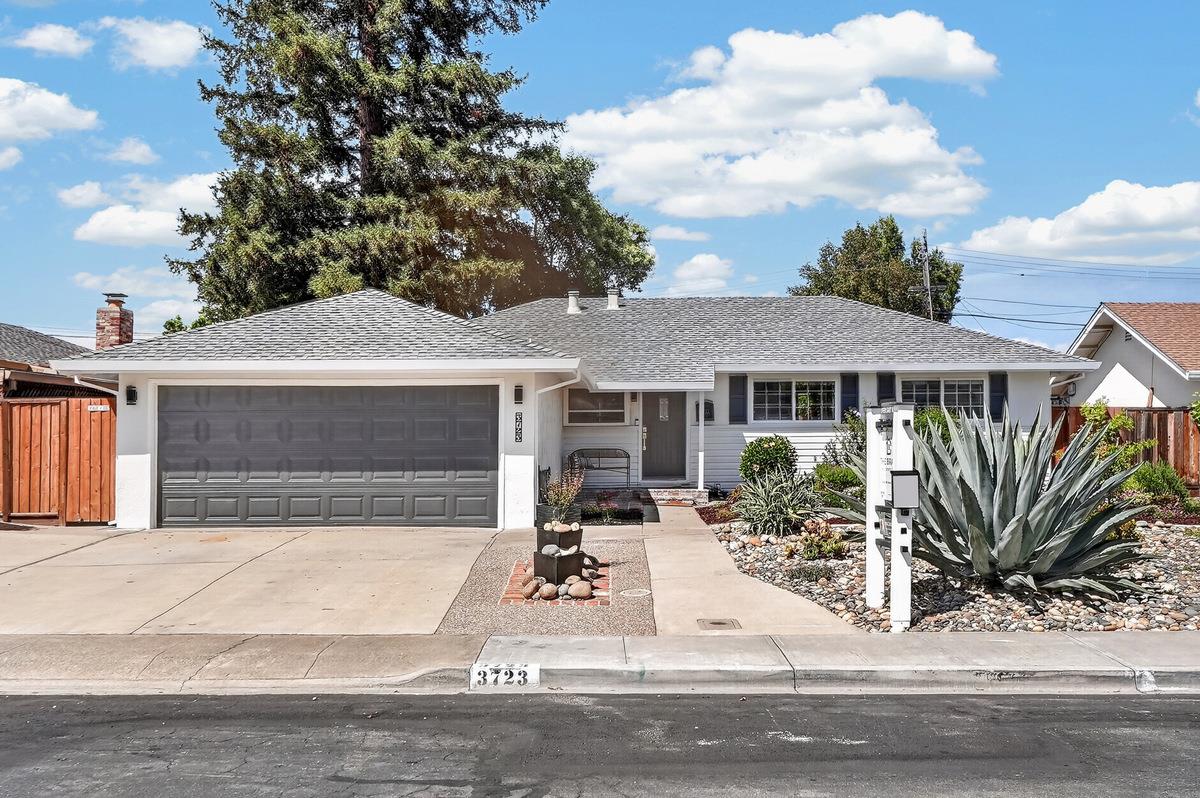 Single-story house with a wide gray garage and rock landscaping around a large agave.