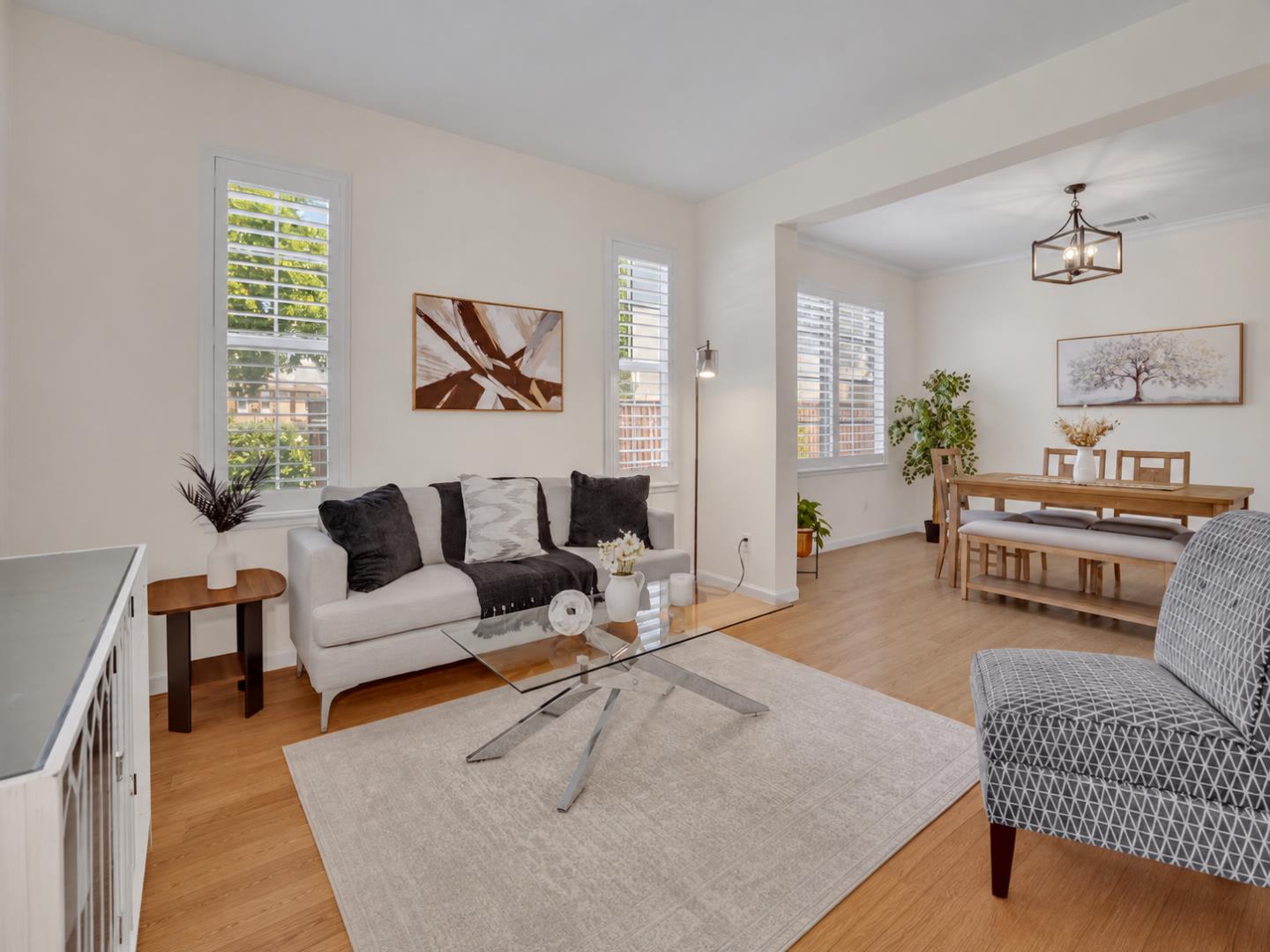 Open-plan living and dining room with shuttered windows, hardwood floors, and a wooden dining set.