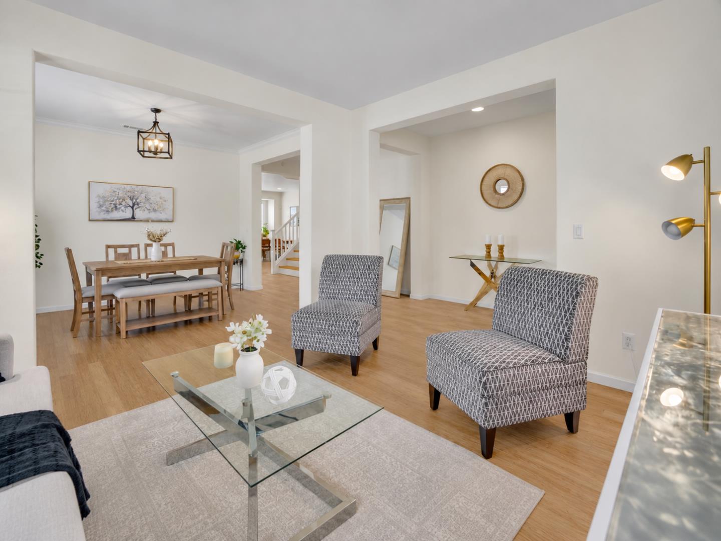 Open-plan living and dining room with patterned armchairs, a glass coffee table, and light wood floors.