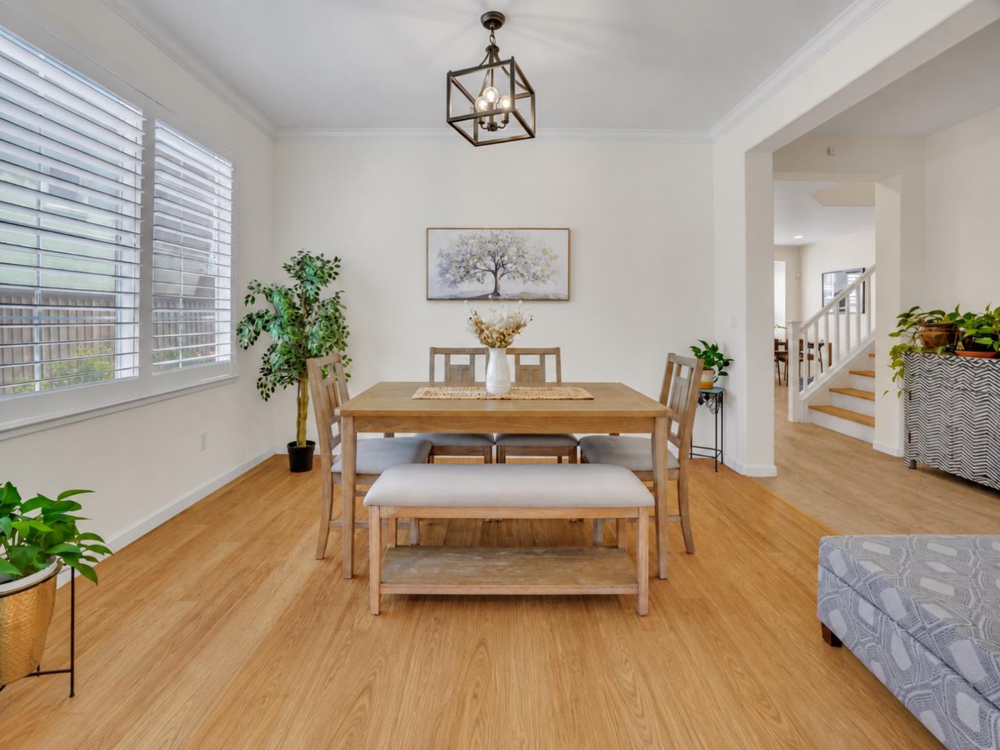 Dining room with a wooden table and bench, shuttered windows, and light hardwood flooring.