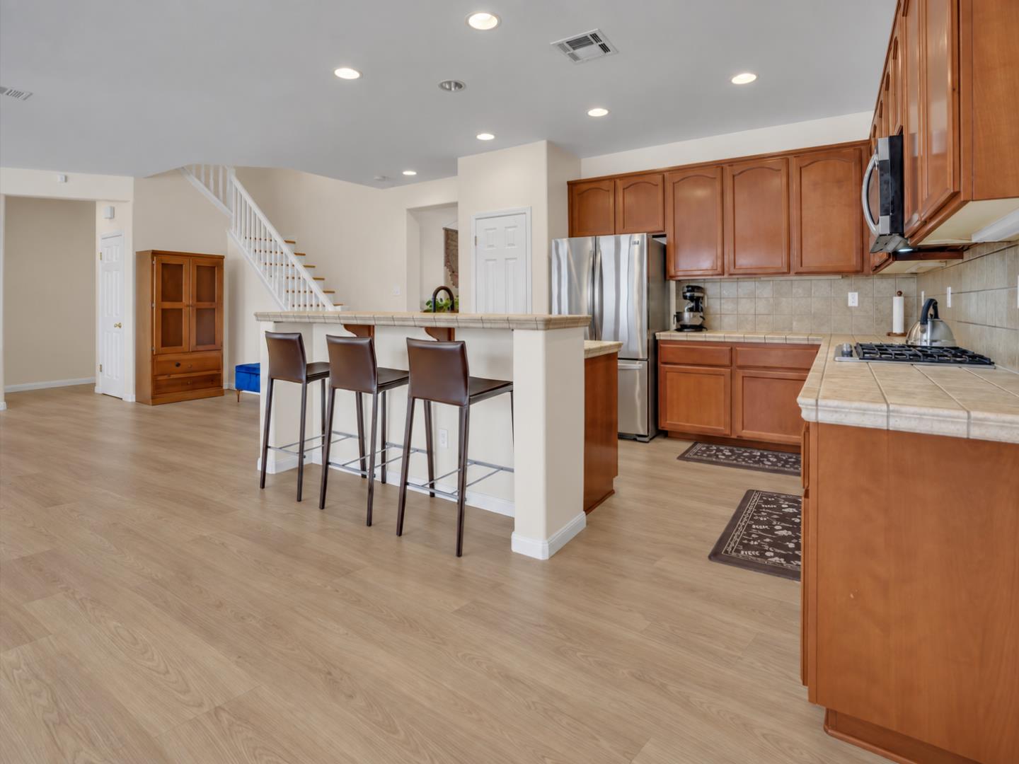 Kitchen with wood cabinets, stainless steel appliances, and a breakfast bar with three stools.