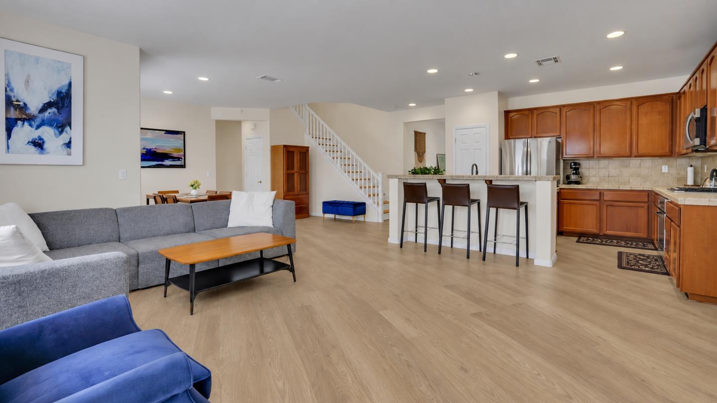 Open-plan living room and kitchen with a gray sectional, wood cabinetry, and a breakfast bar.