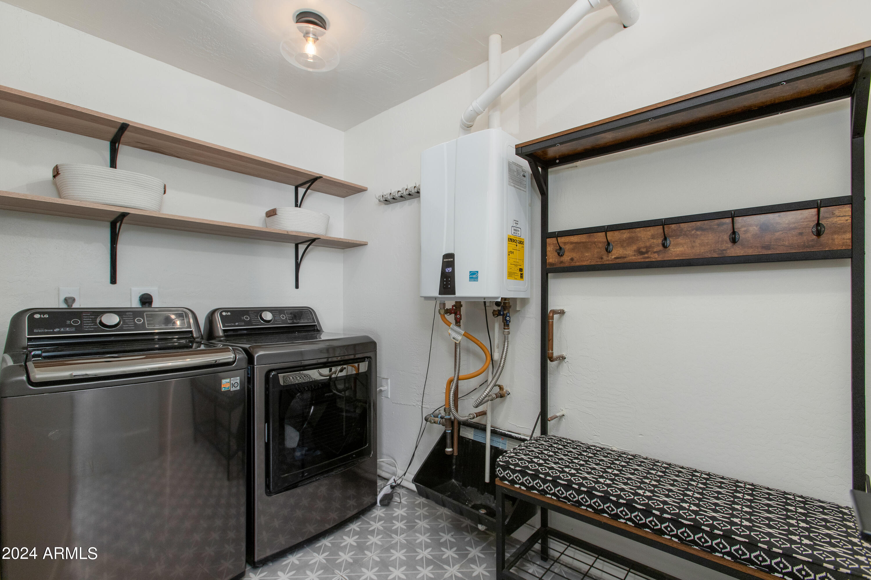 Laundry room with a washer and dryer, open shelves, wall hooks, and a patterned bench.