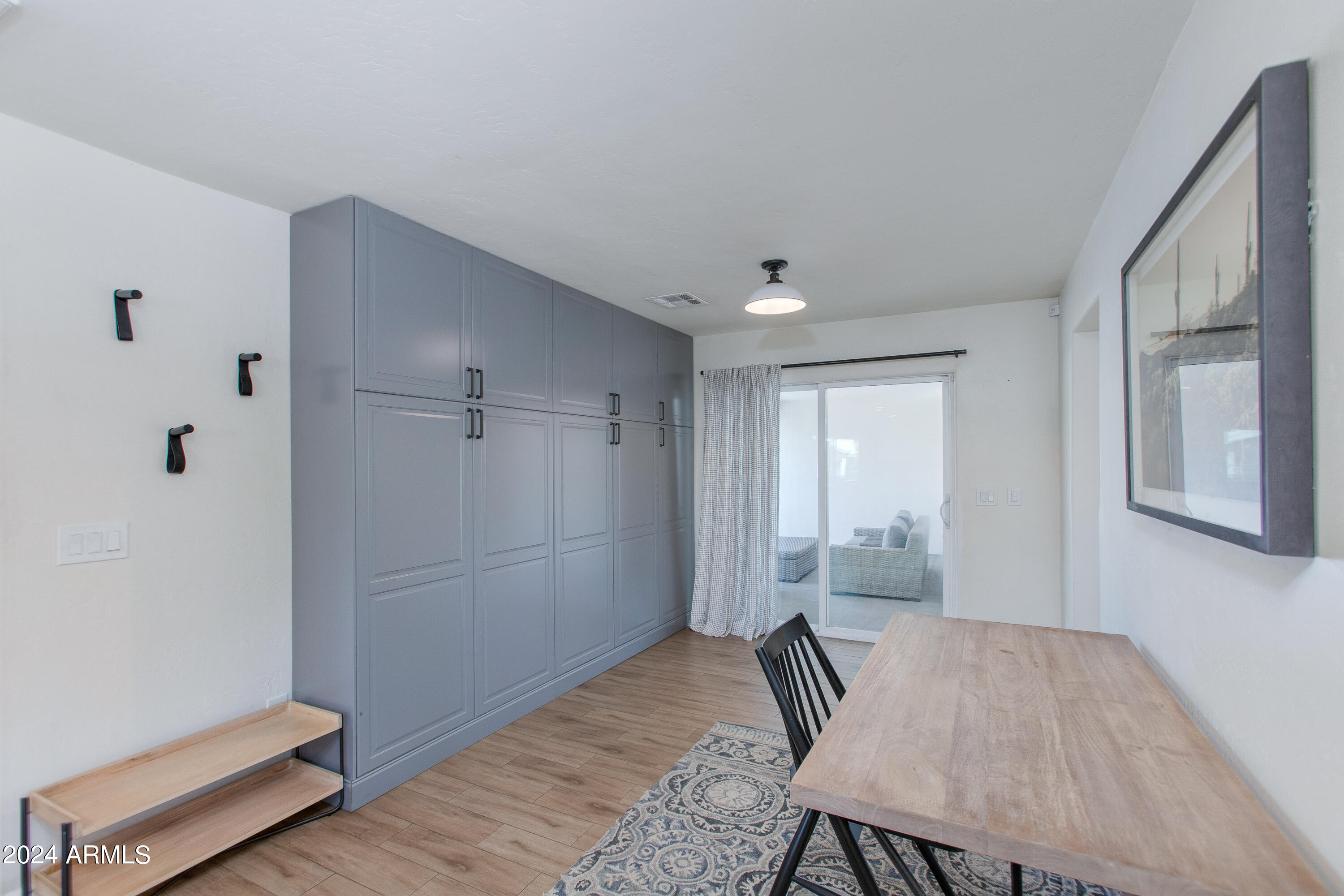 Dining area with gray built-in cabinets, a light-wood table, patterned rug, and sliding doors to a patio.