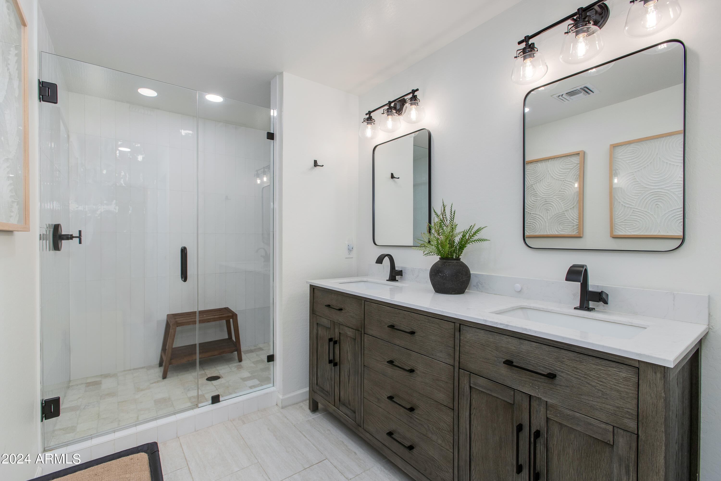 Bathroom with a glass walk-in shower and double vanity with dark wood cabinets and black fixtures.