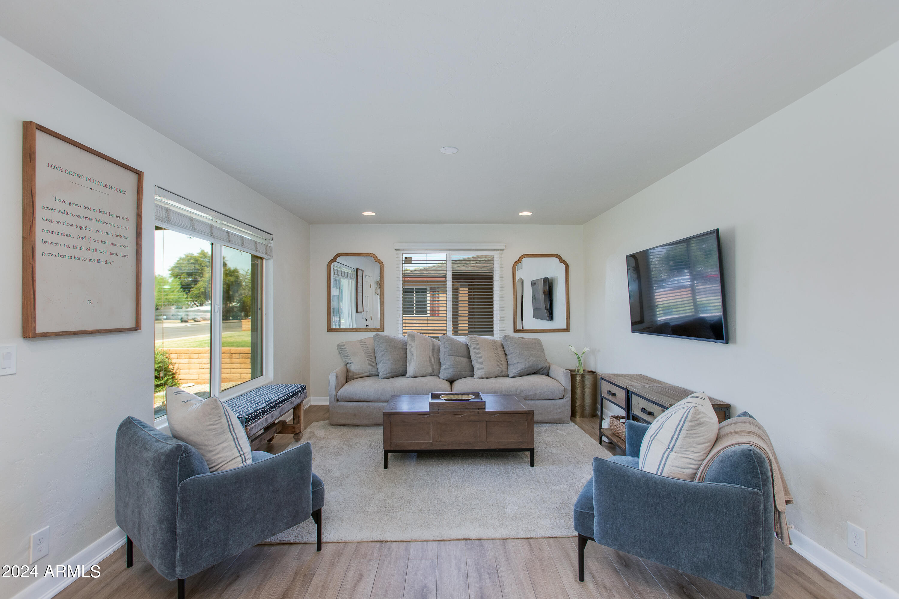 Furnished living room with a gray sofa, blue armchairs, and sliding glass doors.