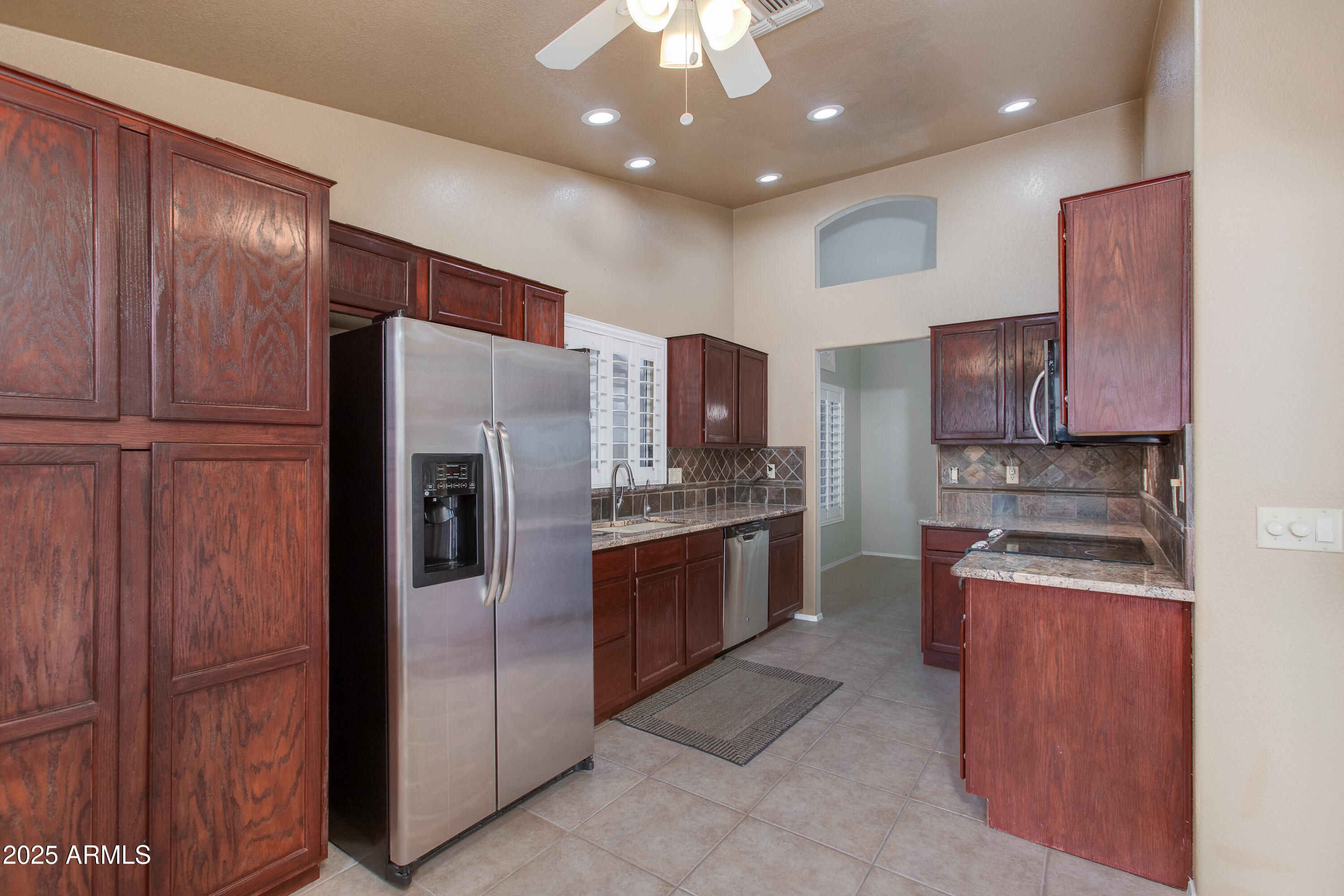 Kitchen with dark wood cabinets, granite counters, stainless steel appliances, and tiled backsplash.