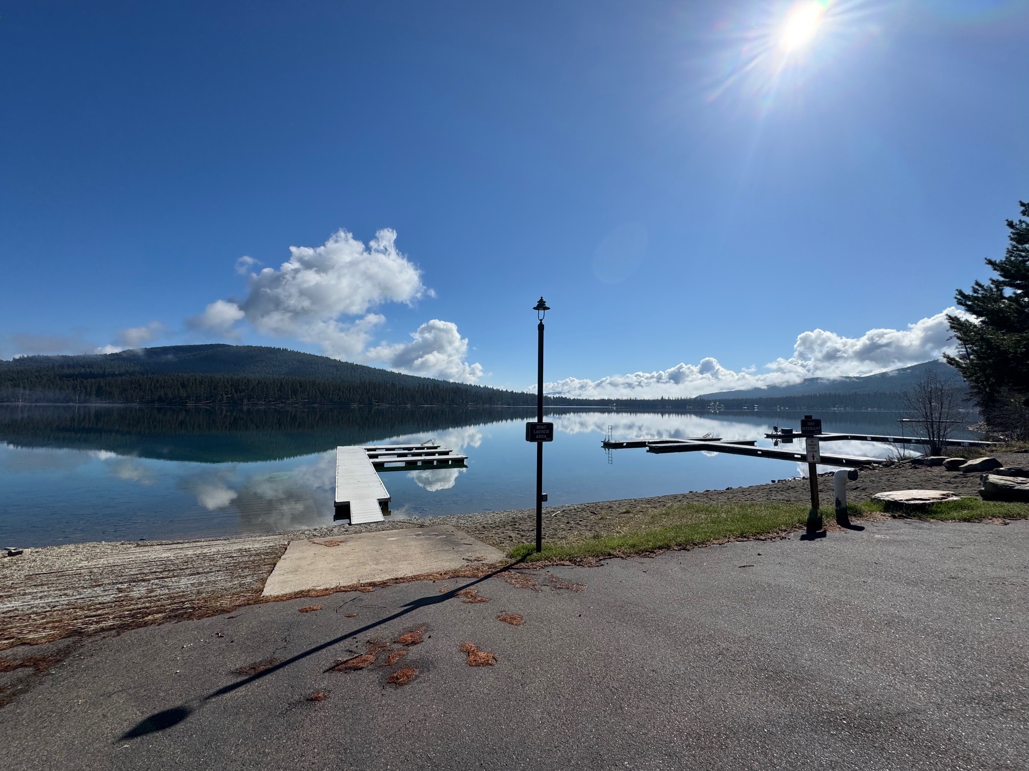 Lakefront docks extend into a calm, reflective lake, with forested hills beyond.