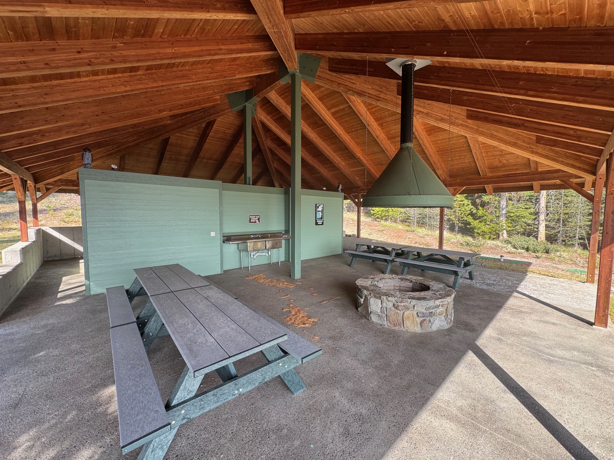 Covered pavilion with picnic tables, a stone fire pit, and a built-in sink.