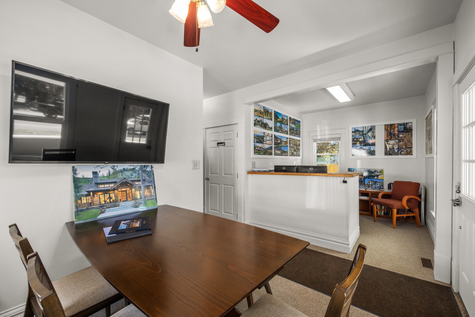 Office meeting area with a large conference table, reception counter, and framed property photos.
