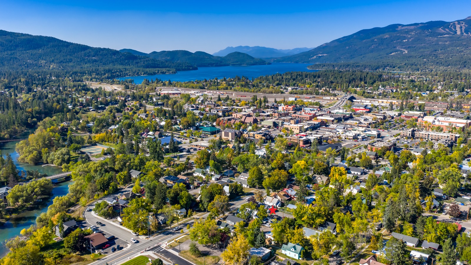 Aerial view of Whitefish with the property marked by a red star, near the lake and mountains.