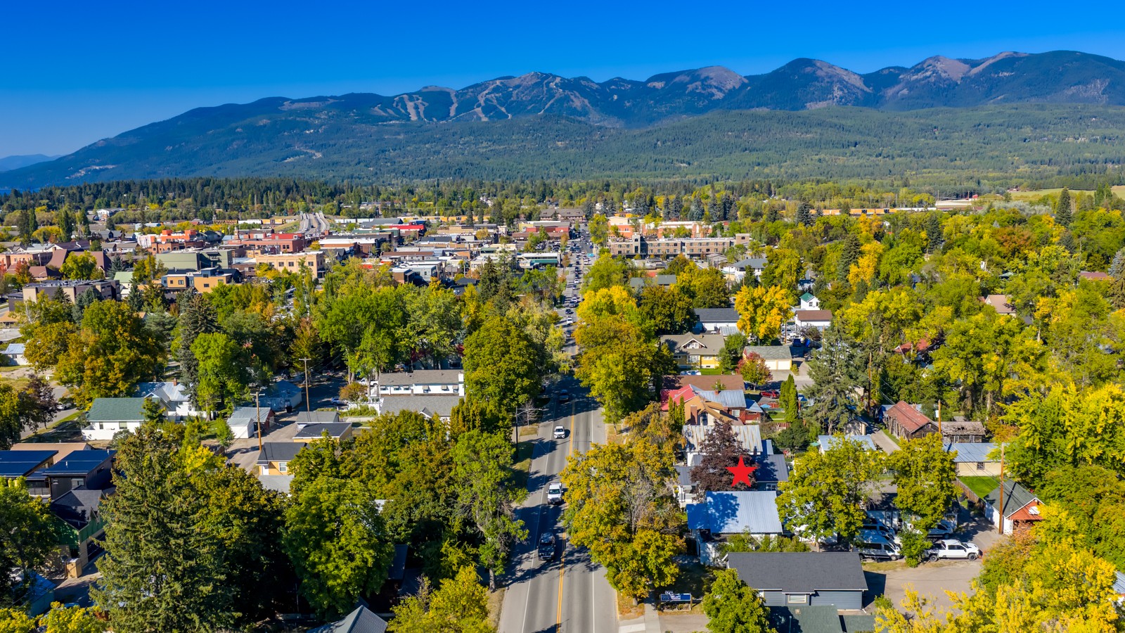 Aerial view of the property marked by a red star, with downtown and mountains beyond.