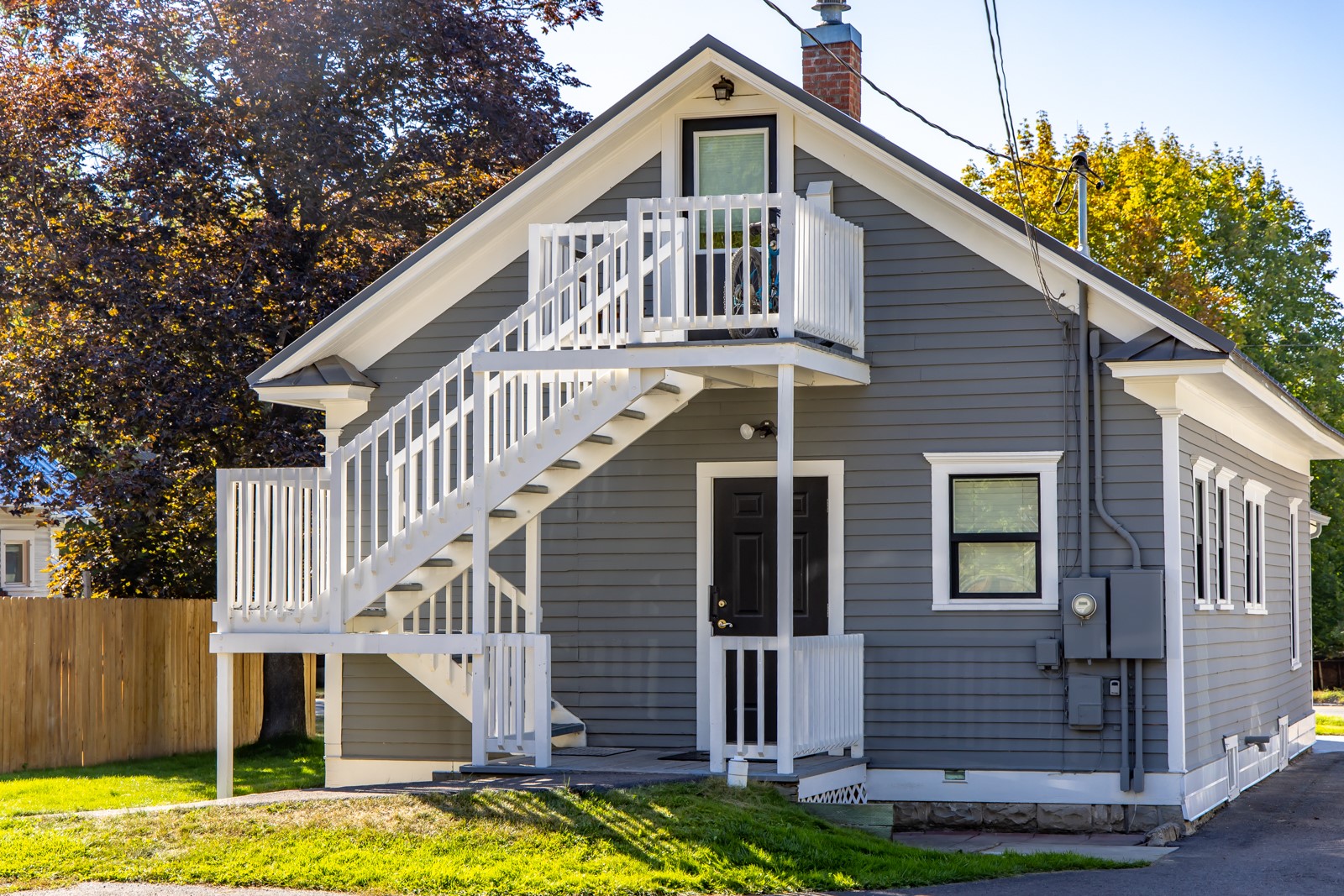 Gray house with white exterior stairs leading to an upper balcony.