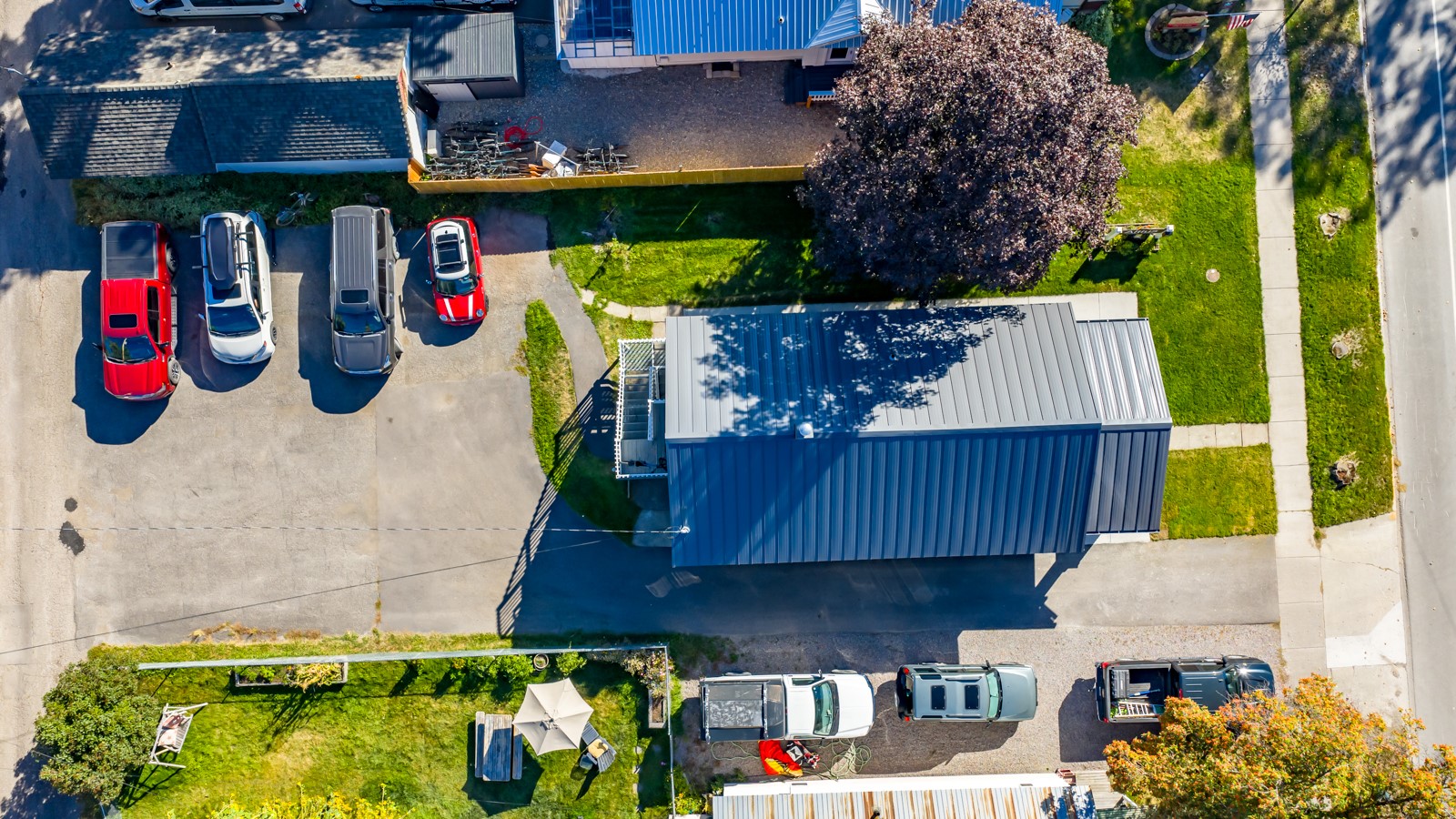 Aerial view of a blue metal-roofed building, parking area, and surrounding yards.