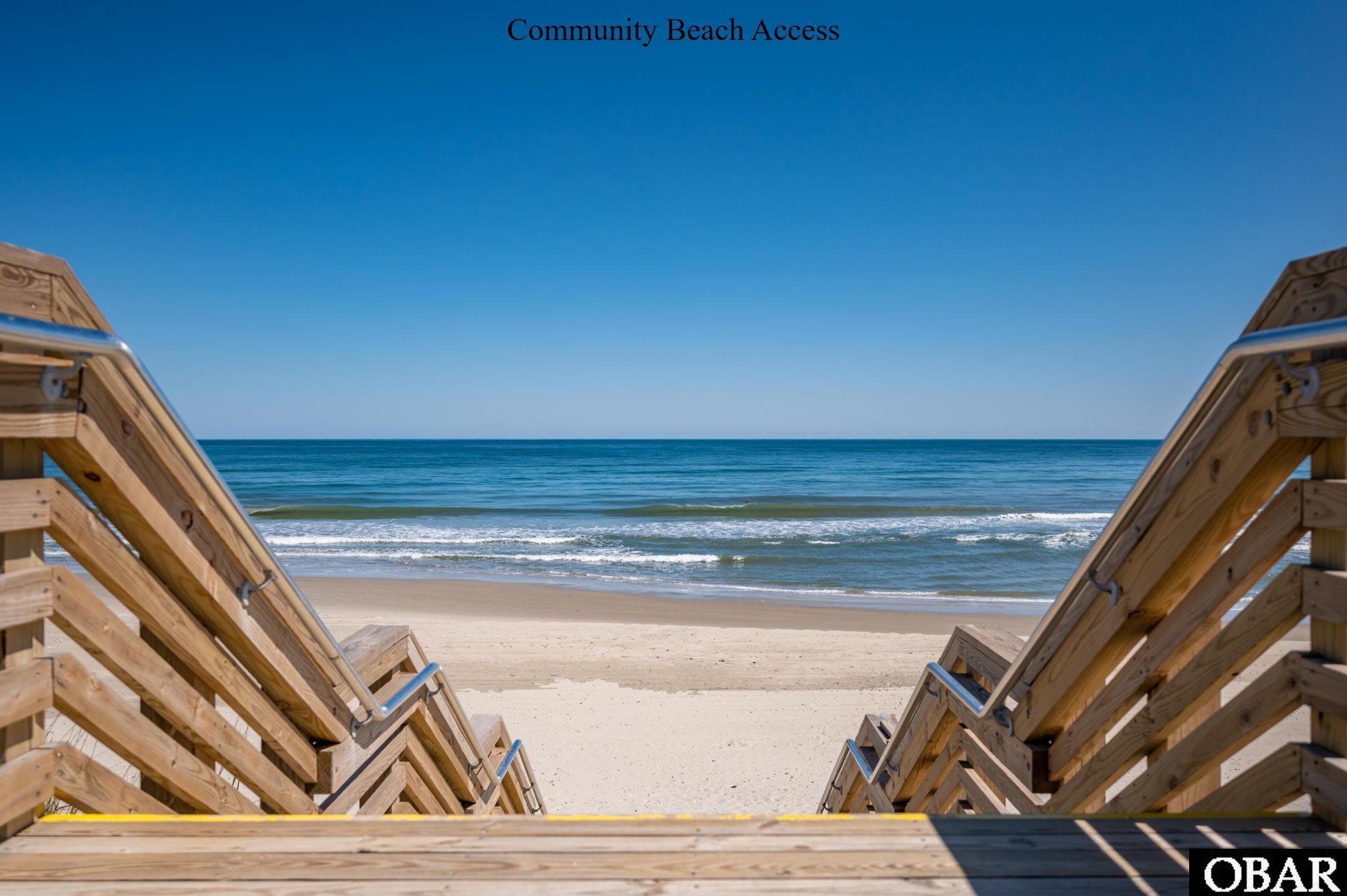 Wooden beach access stairs frame a sandy beach and ocean shoreline.