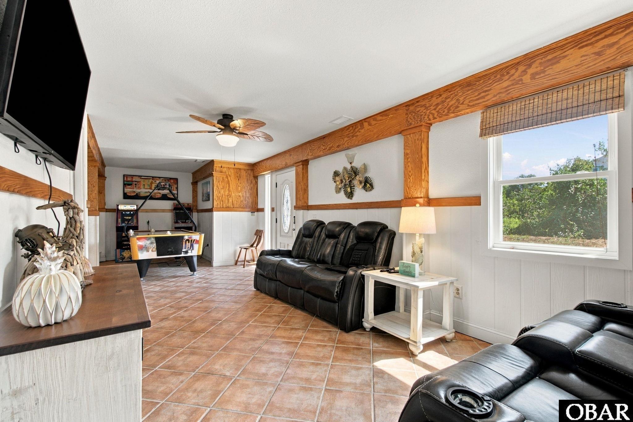 Furnished recreation room with terracotta tile floors, black leather recliners, and a pool table.