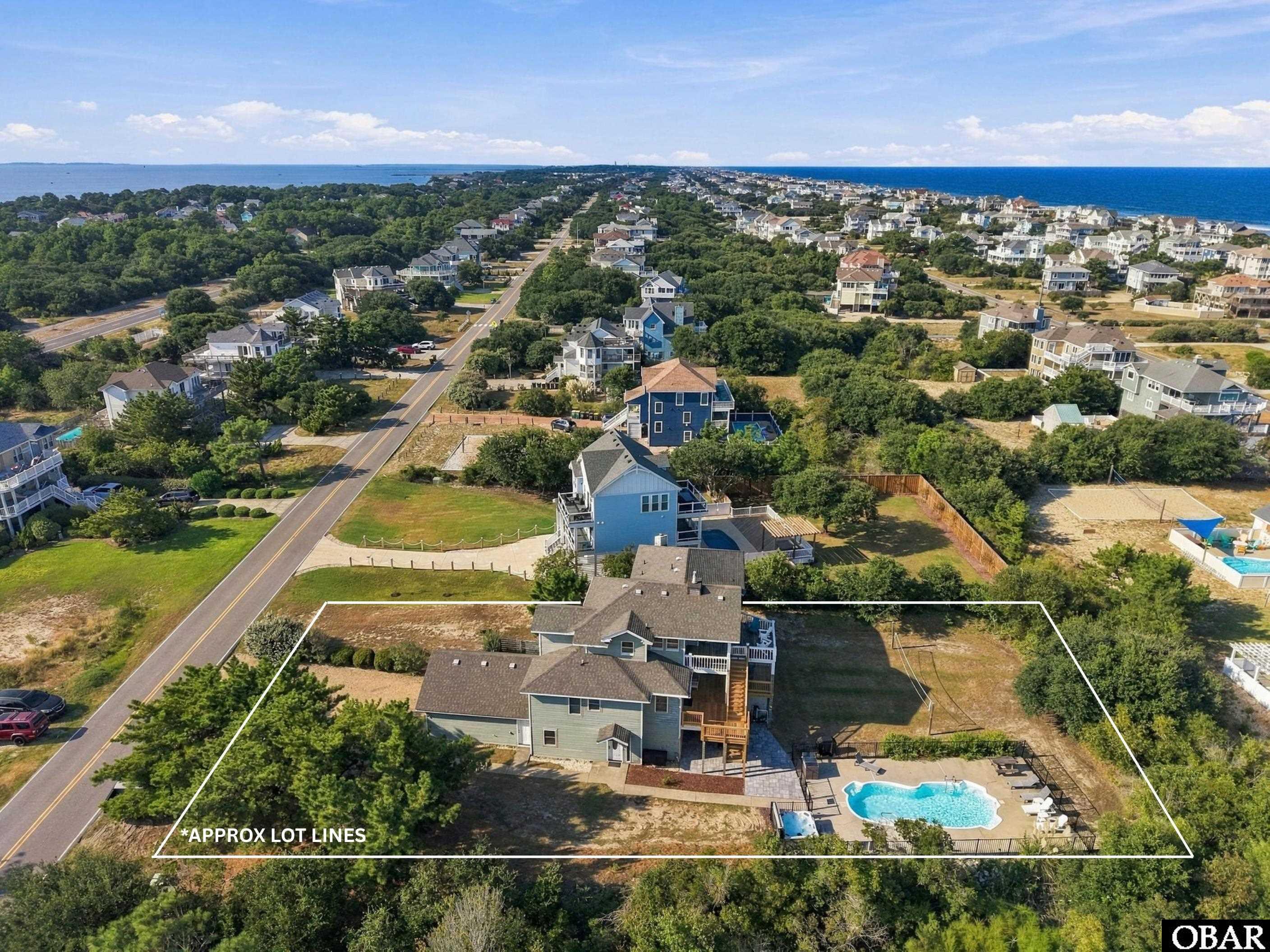 Aerial view of a house and pool outlined by approximate lot lines, with the ocean visible beyond the neighborhood.