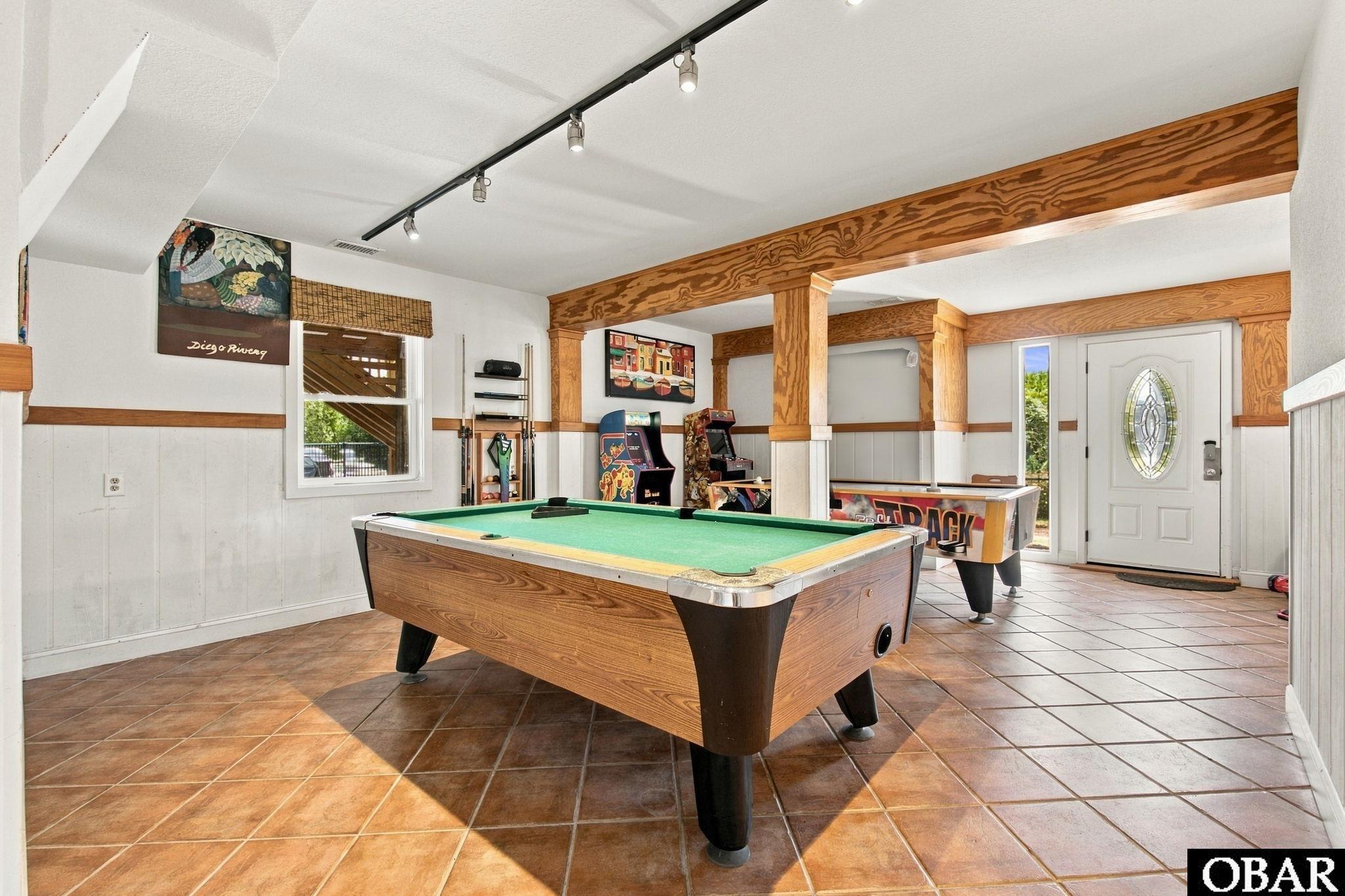 Game room with a pool table, arcade cabinets, and an air hockey table.