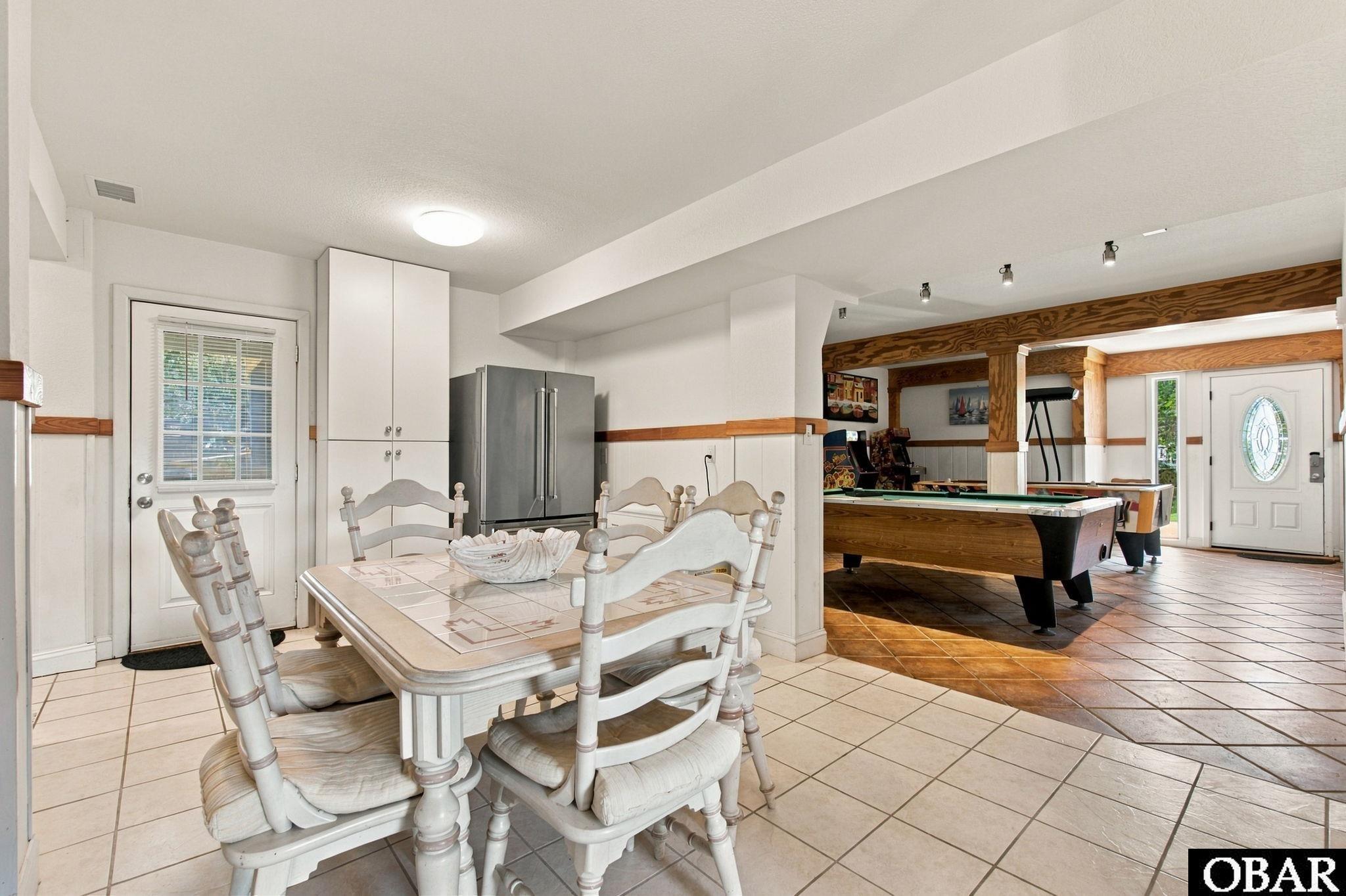 Dining area opening to a recreation room with a pool table and wood trim.