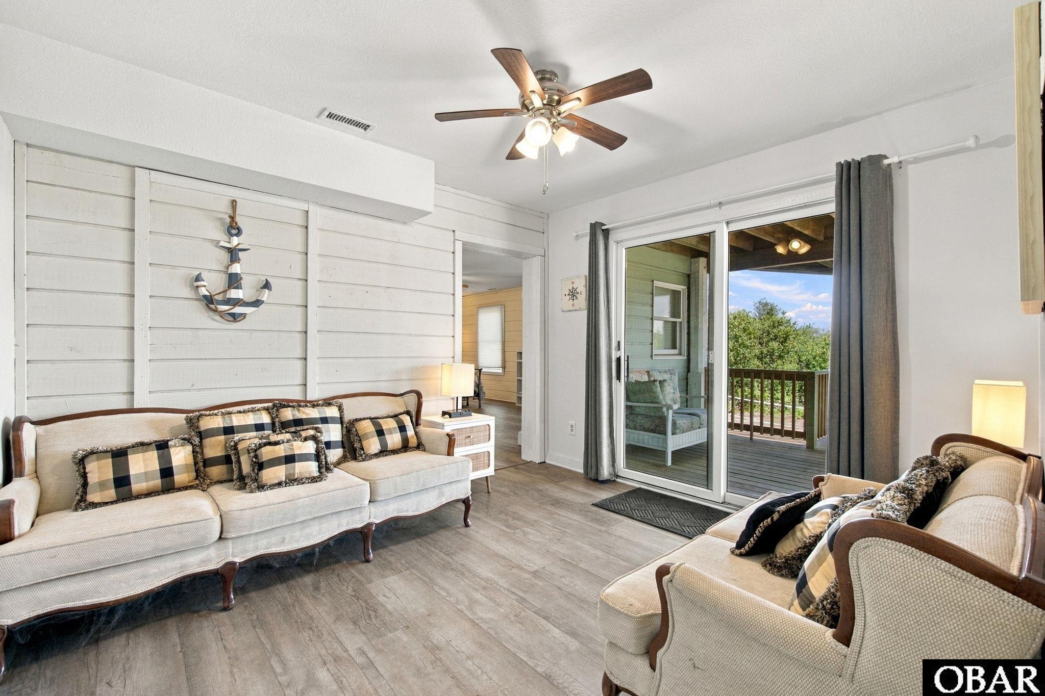 Living room with cream sofas and sliding doors opening onto a deck.
