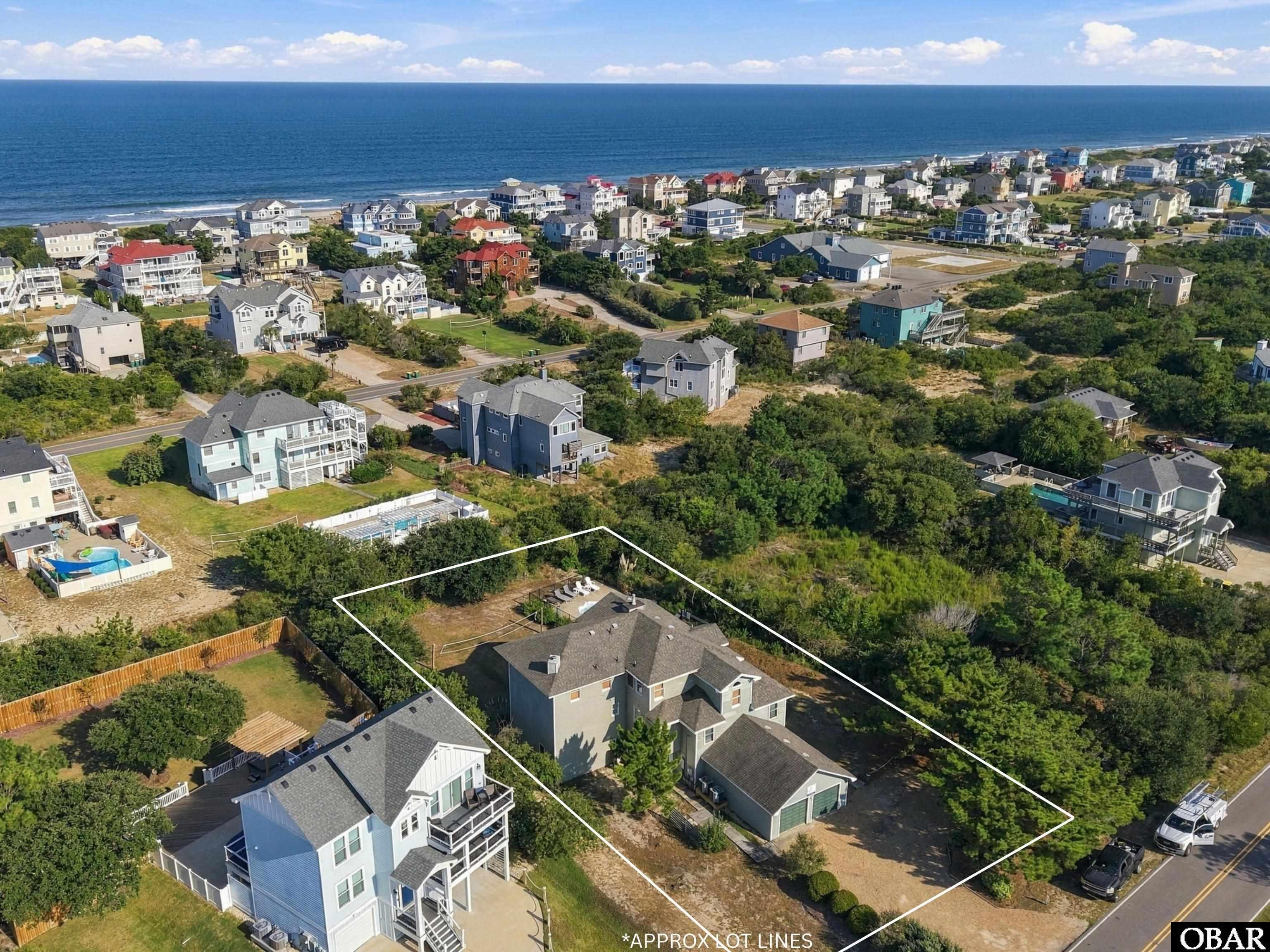 Aerial view of 839 Drive, with approximate lot lines marking the home’s wooded yard near the ocean.