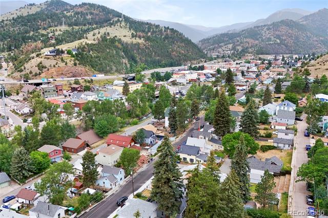 Aerial view of a mountain town with homes, tree-lined streets, and forested hills.