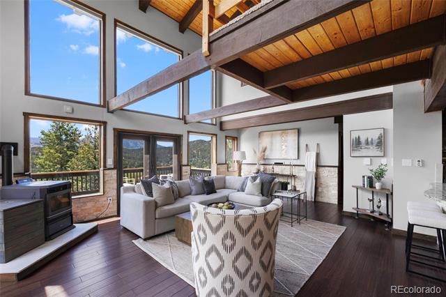 Vaulted living room with exposed beams, tall windows, and a gray sectional sofa.