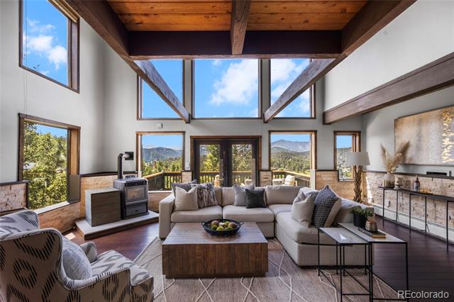Living room with a vaulted wood ceiling, large windows, and mountain views.
