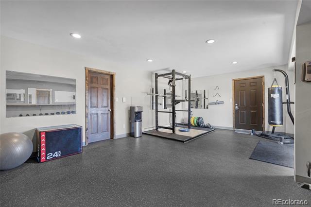Home gym with a weight rack, lifting platform, and hanging punching bag.