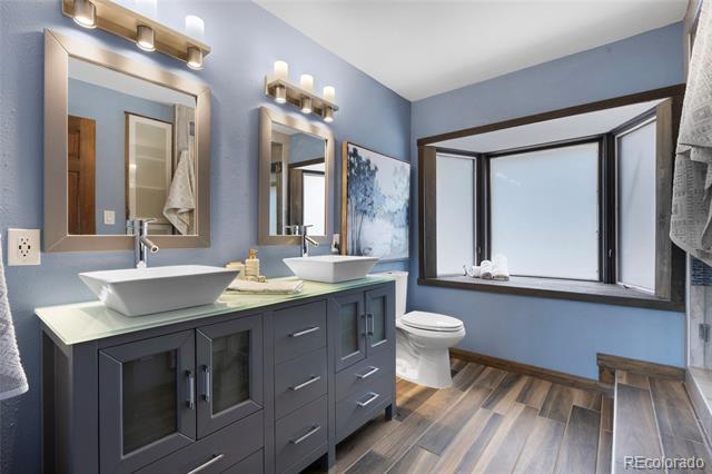 Bathroom with a charcoal double vanity, two vessel sinks, and a large black-trimmed window.