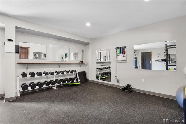 Home gym with mirrored walls and two racks of dumbbells.
