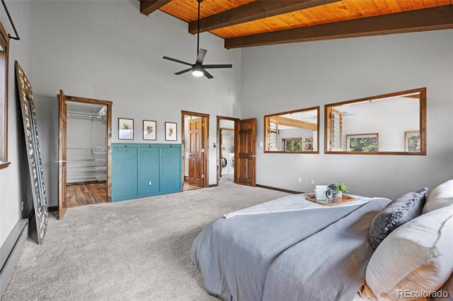 Bedroom with exposed wood ceiling beams, a low platform bed, and teal built-in cabinets.