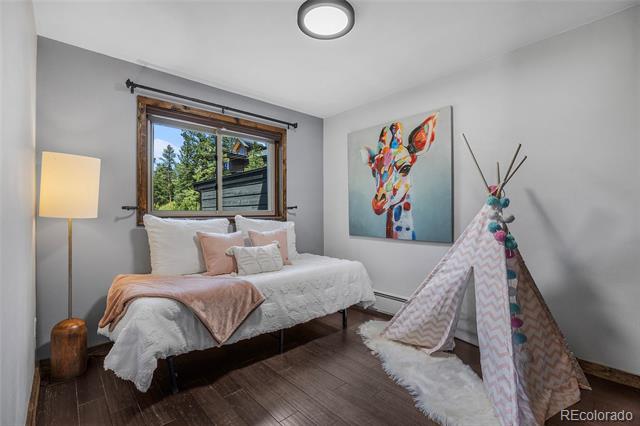 Bedroom with a white bed, blush-pink bedding, colorful animal artwork, and a small play tent.