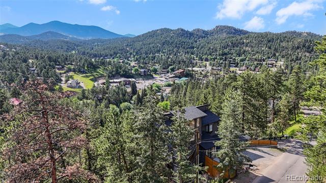 Home among evergreen trees overlooking a mountain neighborhood and forested ridges.