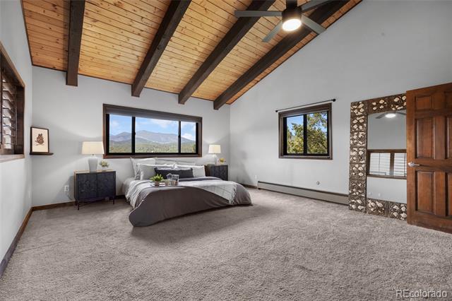 Bedroom with vaulted wood ceiling, exposed beams, and mountain views through the windows.