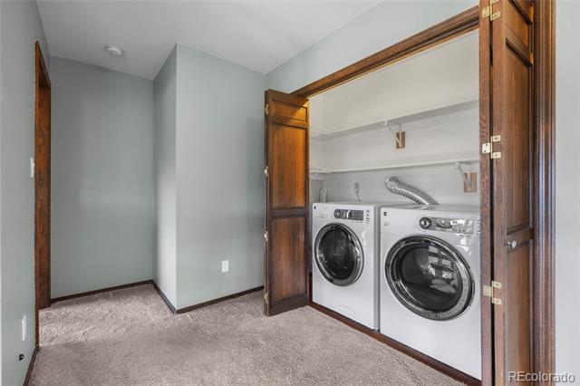 Laundry room with front-loading washer and dryer behind open wooden closet doors.