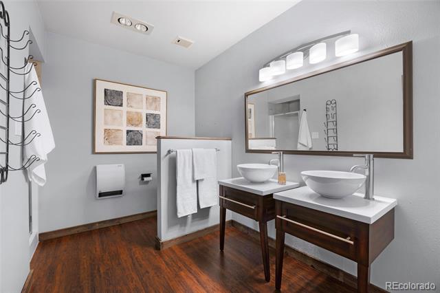 Bathroom with two vessel sinks, dark wood vanities and a wide mirror.