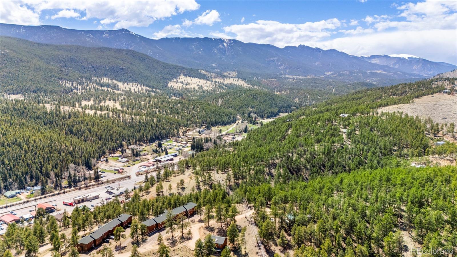 Mountain valley surrounded by forest, with scattered buildings and roads below.