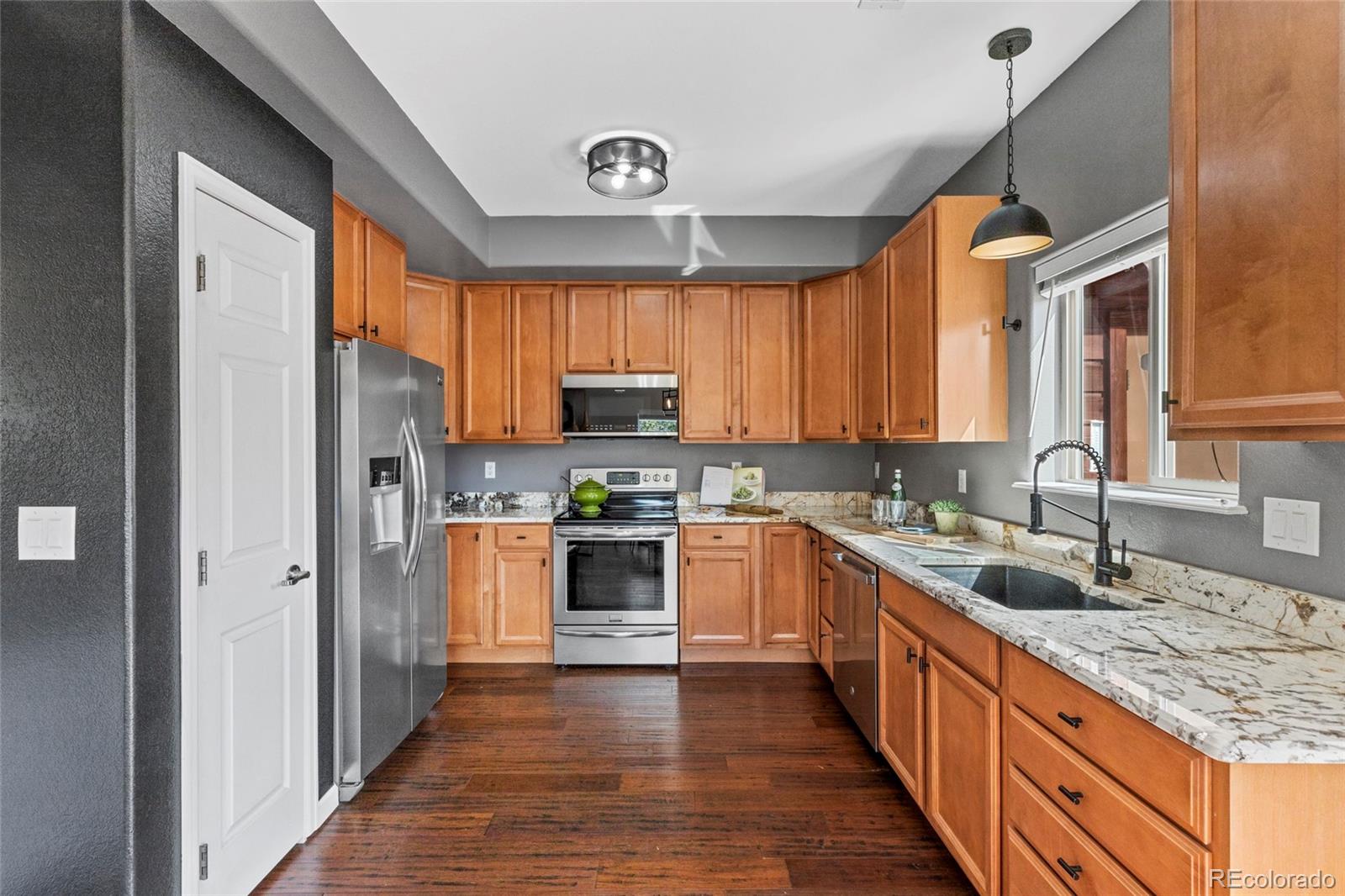 Kitchen with warm wood cabinets, stainless steel appliances, and granite countertops.
