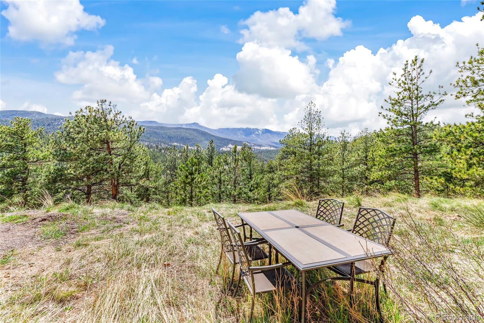 Outdoor dining area overlooking pine-covered hills and distant mountains.