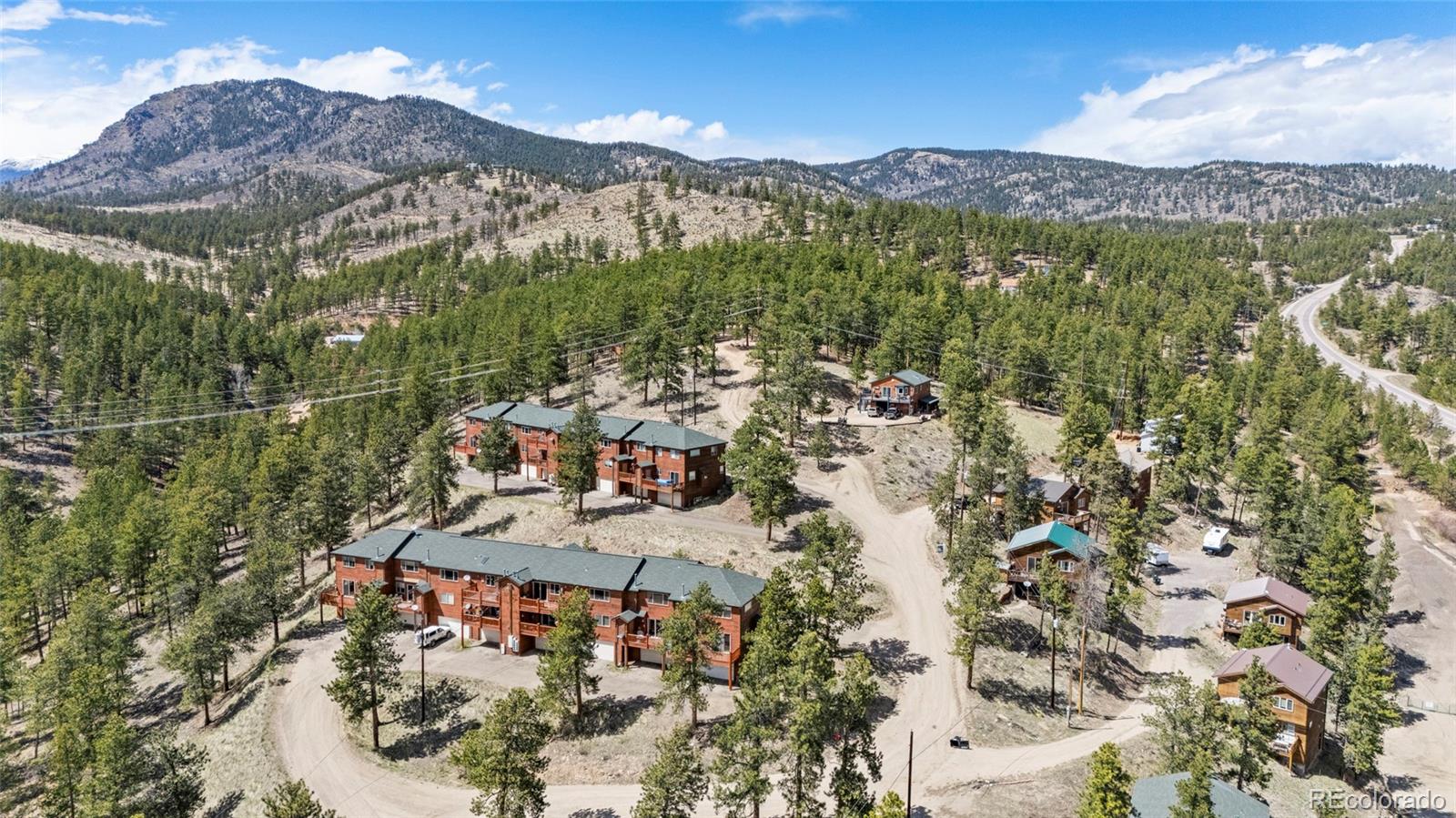 Aerial view of multiunit homes among pine trees, with mountain ridges in the background.