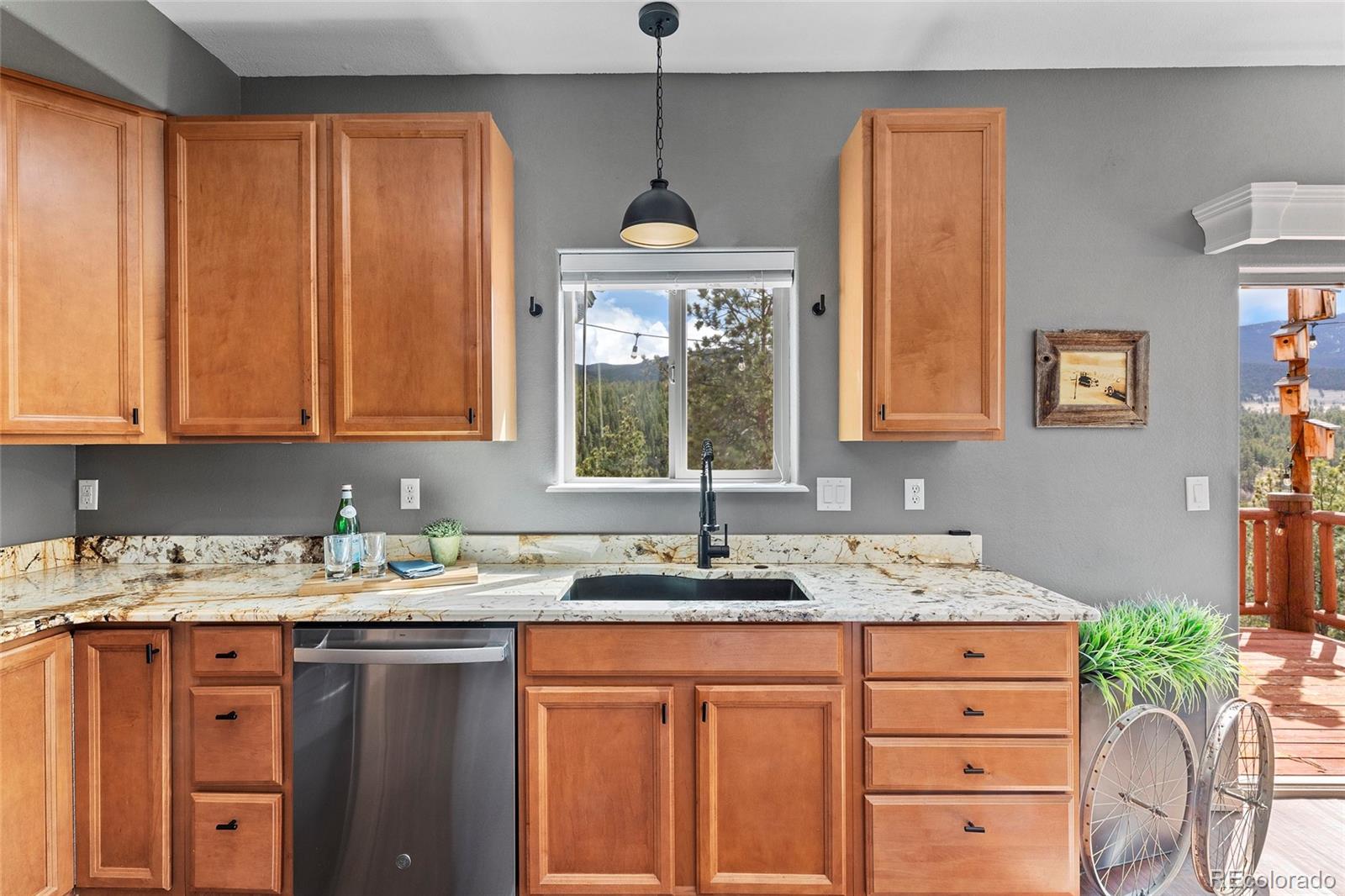 Kitchen with warm wood cabinets, patterned stone counters, and a mountain view through the sink window.