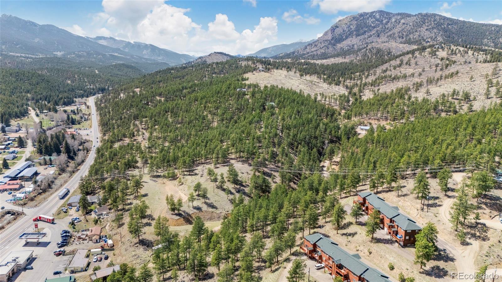 Aerial view of a wooded mountain neighborhood and scattered homes beneath mountain ridges.