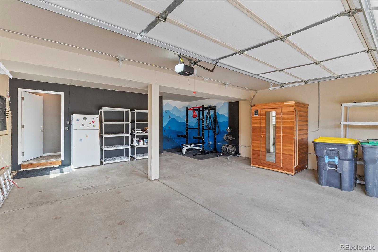 Garage with a weight-training area, blue mountain mural, and wooden sauna.