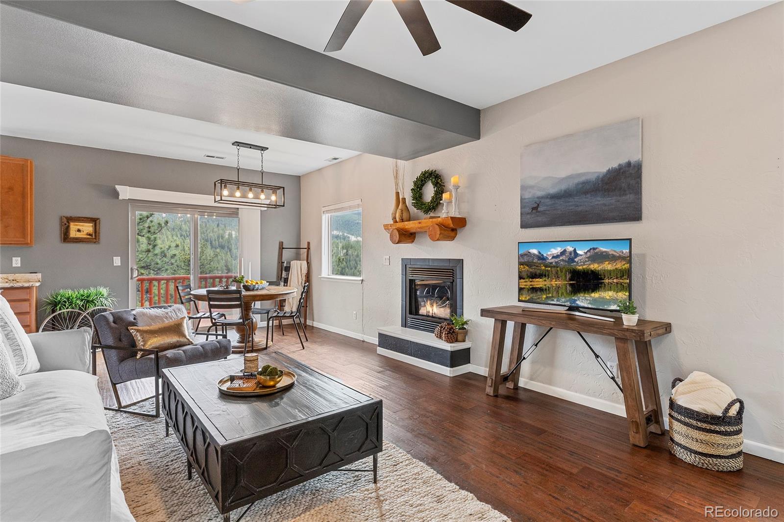 Living room with a fireplace, wood floors, and mountain views through windows beside the dining area.